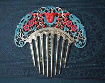 May include: A silver hair comb with a decorative design of flowers and leaves. The flowers are red and blue with a teal enamel finish. The comb has five tines.