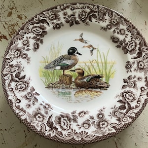 Può includere: Una tazza di ceramica bianca con un manico nero e la scritta "But First, Coffee" in stile scritto a mano. La tazza è su una superficie bianca. La tazza è alta 10 cm.