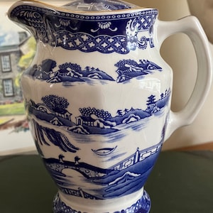 Puede incluir: Una tetera de porcelana azul y blanca con tapa y asa. La tetera presenta un diseño tradicional de paisaje chino con un esquema de color azul y blanco.