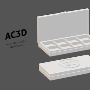 May include: A 3D-rendered, light gray jewelry box with eight compartments, open to display the interior. A matching closed box with a logo is below. The text "AC3D Art-chitecture3D Miniatures" is on the left.