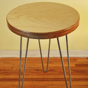 Puede incluir: Una mesa redonda de madera con un acabado de madera natural y tres patas de horquilla. La mesa est&aacute; hecha de madera contrachapada y tiene un dise&ntilde;o simple y moderno.