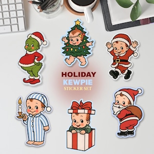 Może przedstawiać: Zestaw sześciu świątecznych naklejek Kewpie. Naklejki przedstawiają kreskówkowe dzieci przebrane za Świętego Mikołaja, choinkę i w piżamie. Naklejki są w kolorach czerwonym, zielonym i niebieskim z napisem "HOLIDAY KEWPIE STICKER SET".
