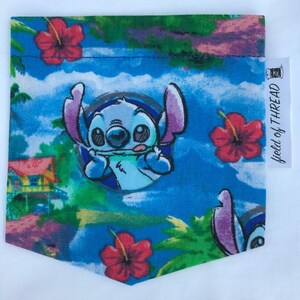 May include: A blue fabric pocket with a colorful tropical print featuring Stitch from Lilo & Stitch. The pocket has a green, blue, and pink background with red hibiscus flowers and palm trees. The text "World of Thread" is on a white tag attached to the pocket.