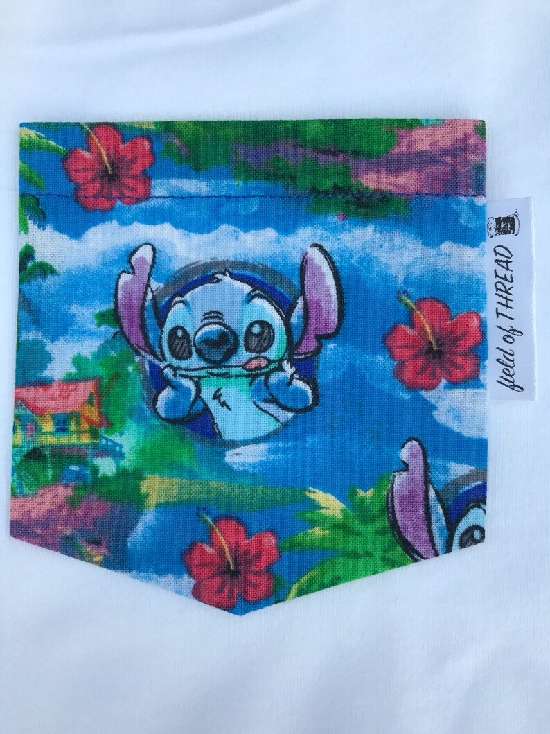 May include: A blue fabric pocket with a colorful tropical print featuring Stitch from Lilo & Stitch. The pocket has a green, blue, and pink background with red hibiscus flowers and palm trees. The text "World of Thread" is on a white tag attached to the pocket.