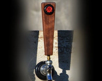 Puede incluir: Una manija de grifo de cerveza de madera con un diseño de rosa negra y roja. La manija está unida a un grifo de cerveza cromado.