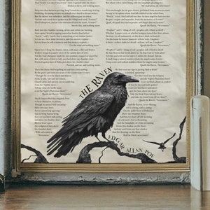 A framed Raven poem print by Edgar Allan Poe leans against a wall on a desk next to dried flowers, a clock, and three books.