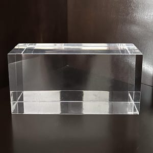 May include: A clear rectangular acrylic block. The block is smooth and has polished edges.