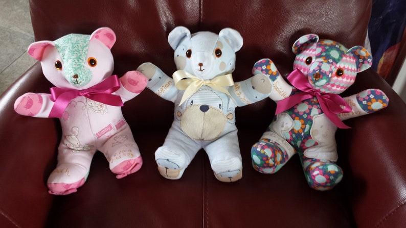 Op de afbeelding: Drie handgemaakte teddyberen gemaakt van stofresten. De beren zitten op een rode leren stoel. De beer links is roze met een roze strik, de beer in het midden is blauw met een gele strik en de beer rechts is veelkleurig met een roze strik.