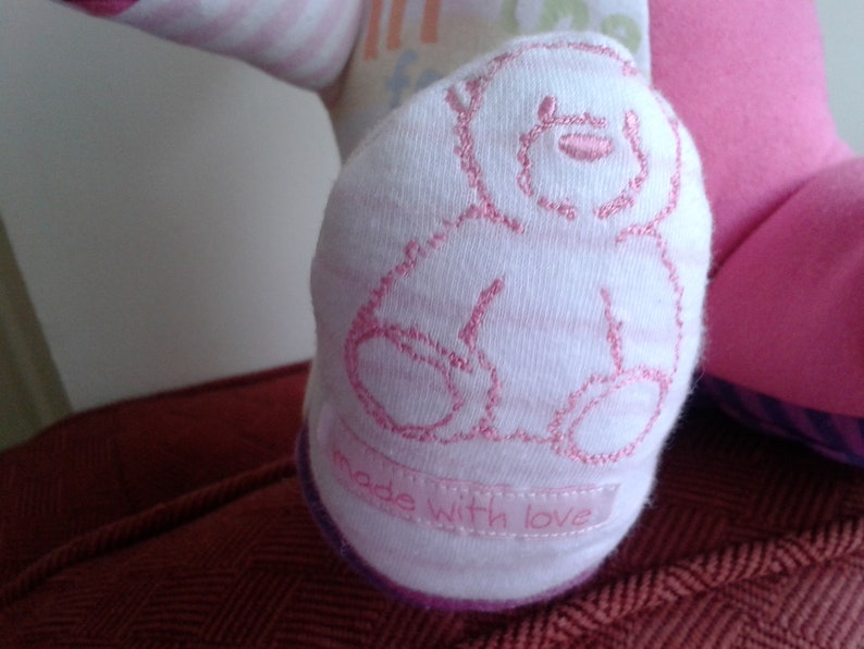 Op de afbeelding: Een witte sok met een roze geborduurd berenontwerp en de tekst "Made with love".