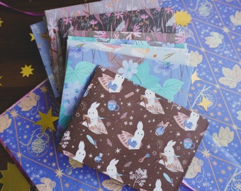 May include: A stack of colourful patterned paper with a brown paper with a white bunny rabbit pattern on top. The paper is decorated with a gold star and the text #tukonitribe.