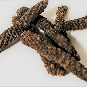 May include: Close-up of dried long peppercorns, a spice with a pungent flavor. The peppercorns are brown and have a rough texture.