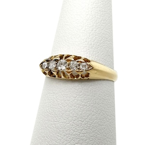 May include: A gold band ring with five clear round diamonds set in a delicate filigree design.