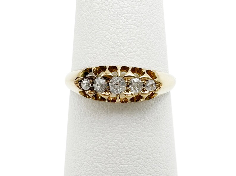 May include: A gold band ring with five small round diamonds set in a scalloped design.