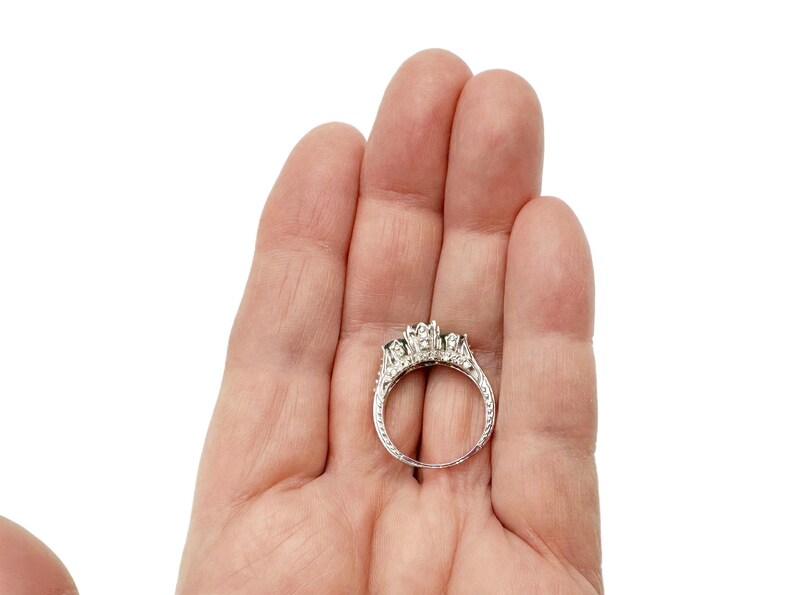 May include: A silver ring with three round stones set in a prong setting. The ring is surrounded by smaller stones.