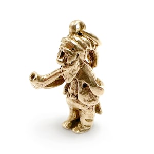 Peut inclure: Un charm doré en forme de gnome, avec un long nez et une barbe, portant un chapeau et une tunique. Le gnome tient une corne à sa bouche. Le charm est fait d'un matériau métallique brillant.