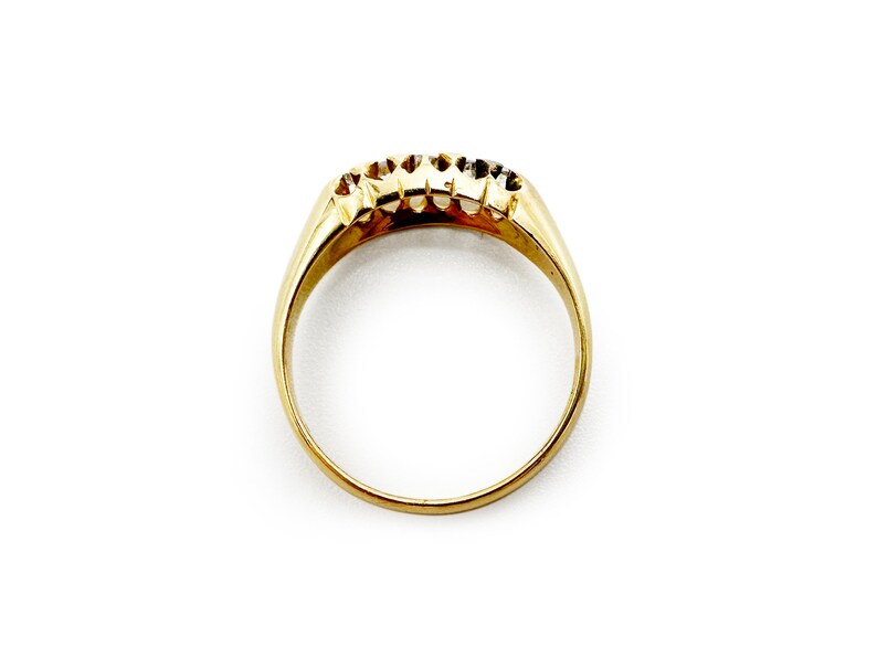 May include: A gold band ring with three small diamonds set in the band.