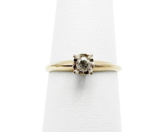 May include: A gold band ring with a single round diamond in the centre.