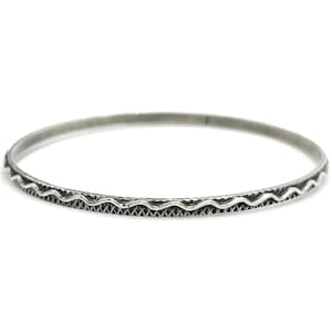 May include: A silver bangle bracelet with a wavy design around the edge.