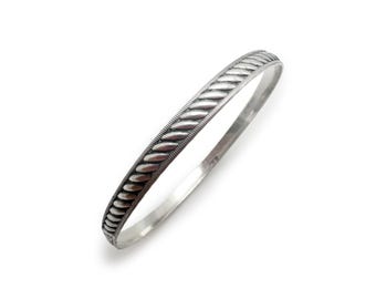 May include: A silver bangle bracelet with a braided design.