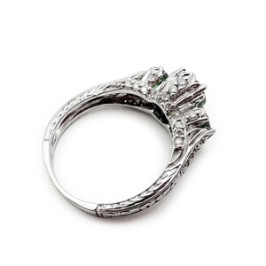 May include: A silver ring with three green gemstones and a diamond band.