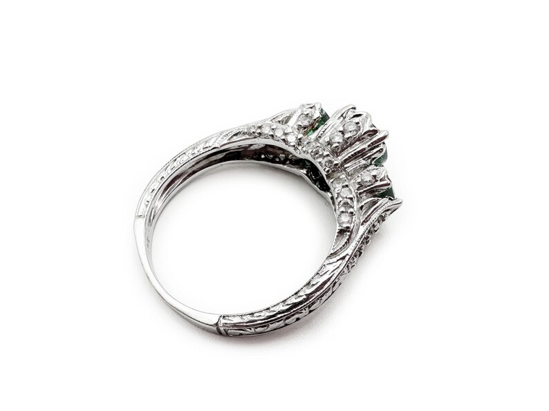 May include: A silver ring with three green gemstones and a diamond band.
