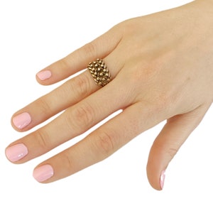 K&ouml;nnte beinhalten: Ein goldener Ring mit einem strukturierten Design. Der Ring besteht aus kleinen, runden Perlen, die zusammengef&uuml;gt sind.