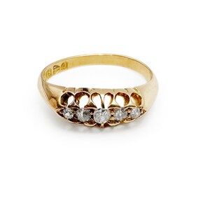 May include: A gold band ring with five small diamonds set in a decorative design.