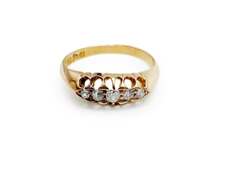 May include: A gold band ring with five small diamonds set in a decorative design.