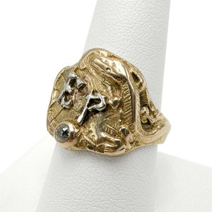 May include: A gold ring with a detailed design featuring a snake, a diamond, and the letters "FP".