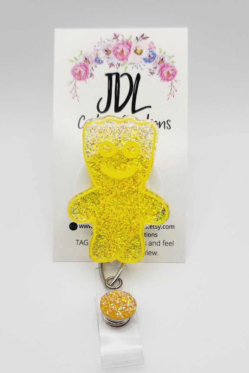 May include: Yellow glitter gummy bear shaped retractable badge holder with a clear plastic badge holder and a silver spring.