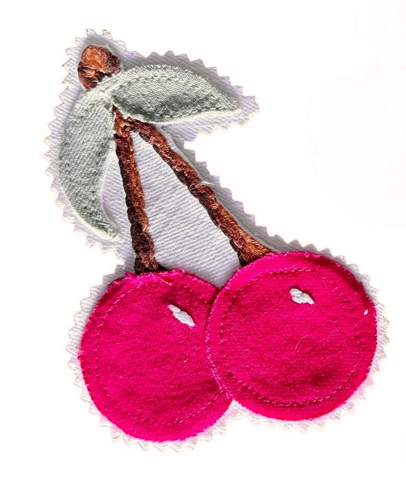 May include: A fabric patch featuring two bright pink circular cherries with brown embroidered stems and a light green leaf. The design is outlined with a white zigzag edge, creating a distinct border around the cherry shape on a white background.