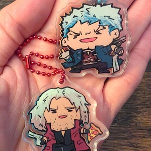 Peut inclure: Deux porte-clés en acrylique transparent avec des illustrations de personnages de dessins animés avec des armes à feu. L'un des personnages a les cheveux bleus et un manteau bleu, l'autre a les cheveux blancs et un manteau rouge, tenant une part de pizza. Les deux porte-clés ont une chaîne rouge et bleue.