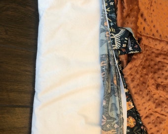May include: A white pillow with a zippered opening, revealing a multi-colored fabric with a woodland animal print. The fabric is folded over and the pillow is lying on a wooden surface.