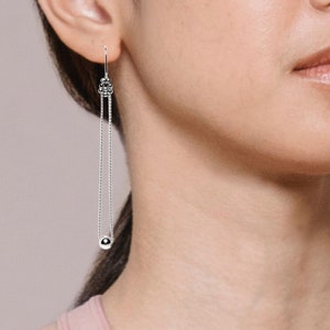 Boucles d'oreilles longues en argent avec boule au bout de la chaine.