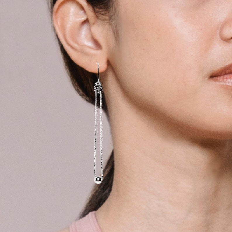 Boucles d'oreilles longues en argent avec boule au bout de la chaine.