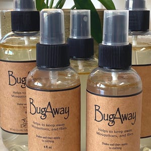 May include: Several clear spray bottles with black caps and brown labels are arranged in a group. The labels read "BugAway" and state the product helps keep away mosquitoes and flies. Each bottle contains 4 fl. oz.