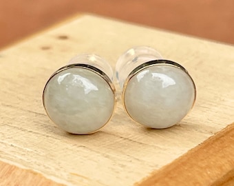 May include: A pair of silver stud earrings with white round gemstones set in a gold bezel.