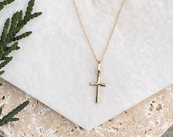 May include: A gold chain necklace with a small, simple gold cross pendant.