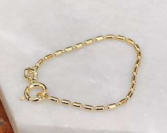 May include: A gold chain bracelet with a lobster clasp closure. The chain is made of small, round links.