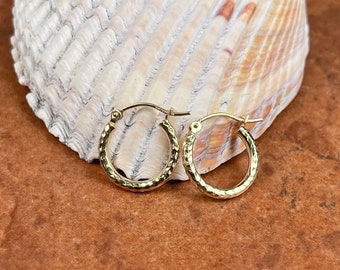 May include: A pair of gold hoop earrings with a hammered texture. The earrings are small and delicate, and they are perfect for everyday wear.