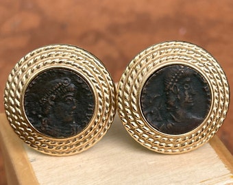 May include: A pair of gold-toned cufflinks with a rope-like design around the edge. Each cufflink features a dark brown coin with a profile of a person's face.