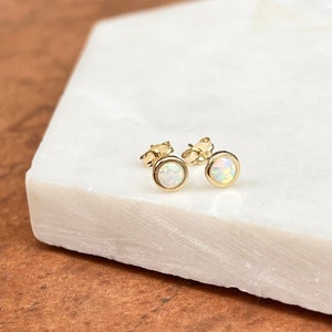 May include: A pair of gold stud earrings with white opal stones.