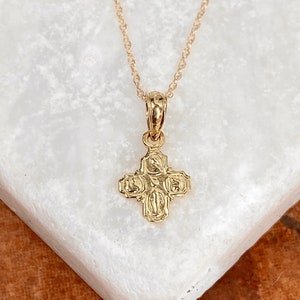 Op de afbeelding: Een gouden ketting met een klein, gedetailleerd kruisje als hanger. Het kruis heeft een getextureerd oppervlak en is een populair religieus symbool.