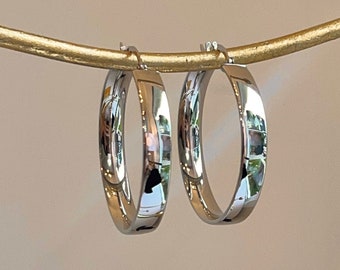 May include: A pair of silver hoop earrings. The hoops are thick and have a polished finish.