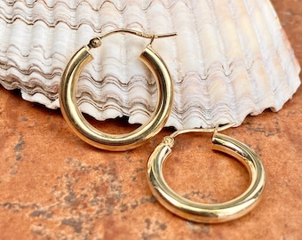 May include: A pair of gold hoop earrings. The earrings are simple and classic, with a smooth, polished finish.