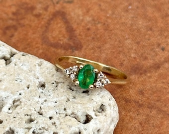 May include: A gold ring with a green oval emerald gemstone surrounded by small diamonds.