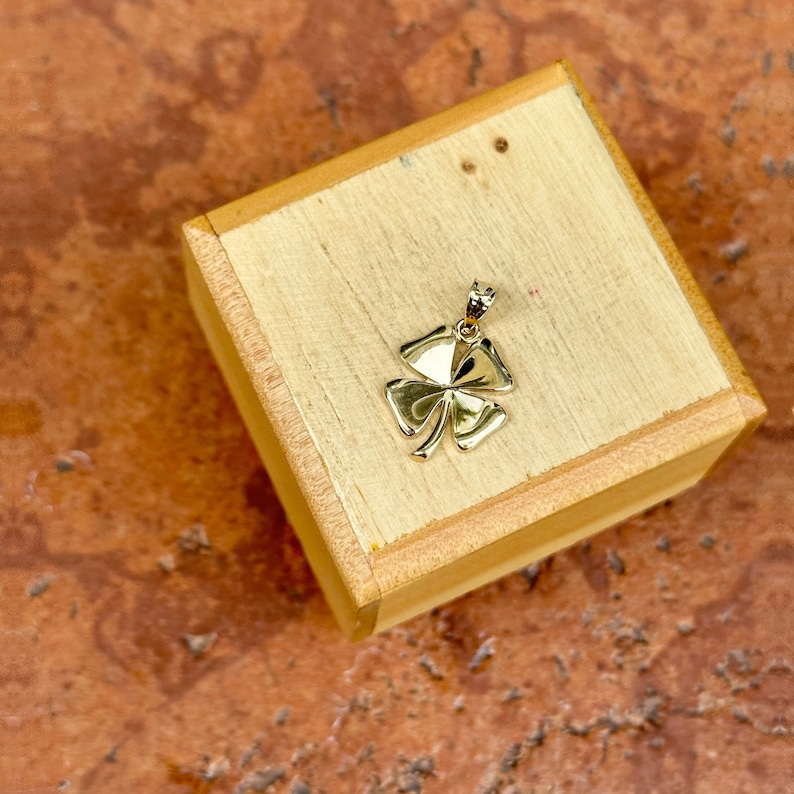 May include: A gold four-leaf clover charm pendant in a wooden box.