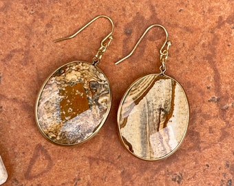 May include: A pair of gold tone earrings with oval shaped brown and white agate stones. The stones have a unique marbled pattern.