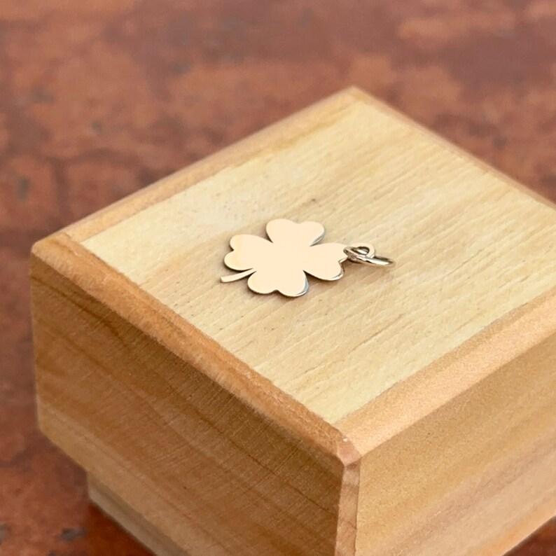 Puede incluir: Un amuleto de tr&eacute;bol de cuatro hojas de oro en una caja de madera.