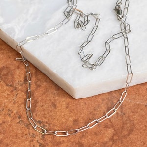 Pu&ograve; includere: Una collana a catena d'argento con un design delicato e collegato. La catena &egrave; composta da piccoli anelli ovali.